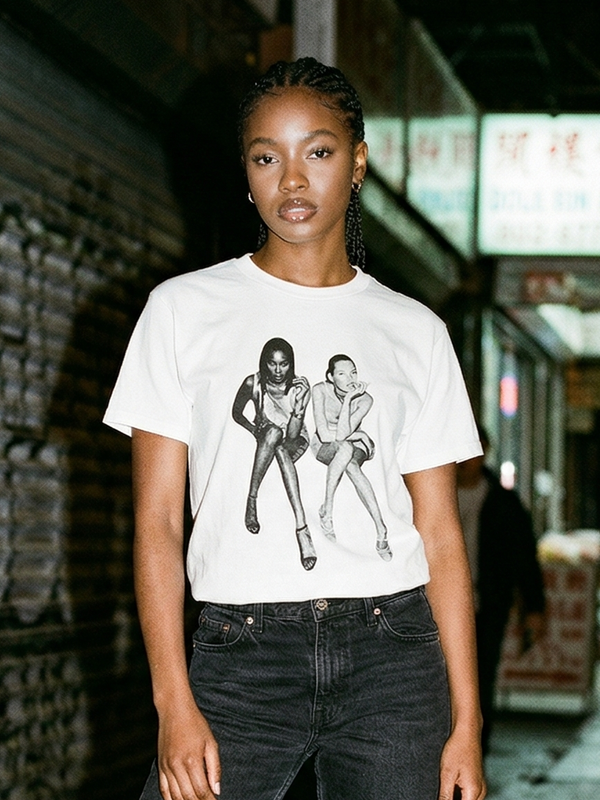 Person wearing a white t-shirt with black graphic design in an urban setting